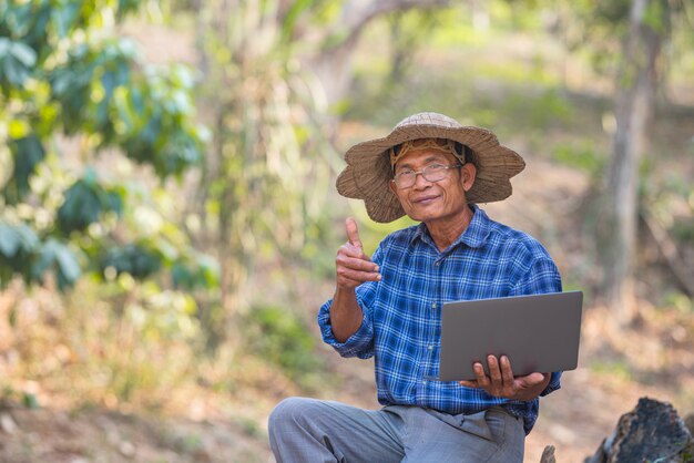 Agriculteur asiatique avec smartphone et ordinateur portable
