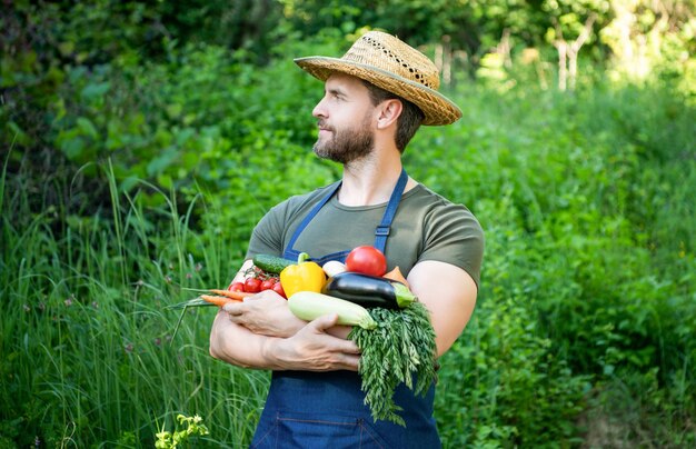 Un agriculteur au chapeau de paille tient des légumes mûrs frais