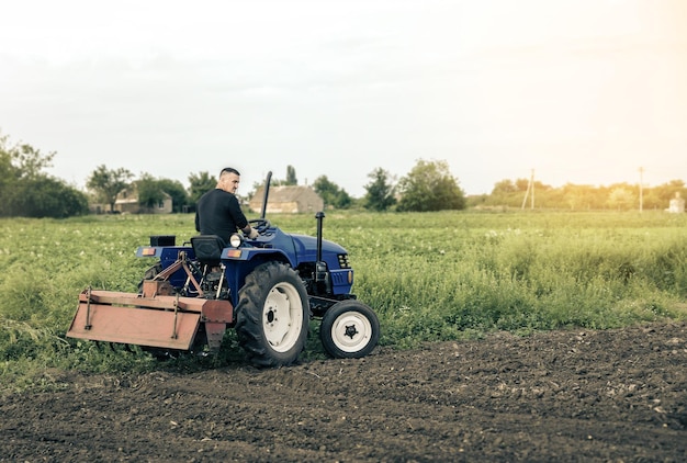 Un agriculteur conduit un tracteur à travers le champ Moulin rectifieuse pour le sol Culture des terres Recrutement et embauche de travailleurs saisonniers pour le travail Agriculture agricole Atténuation de l'amélioration des terres