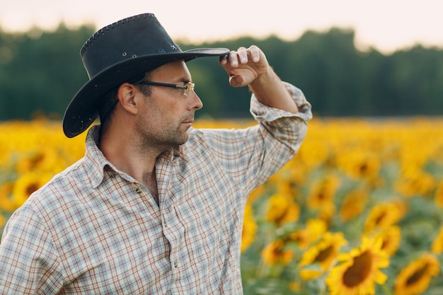 Agriculteur debout dans un champ de tournesol.