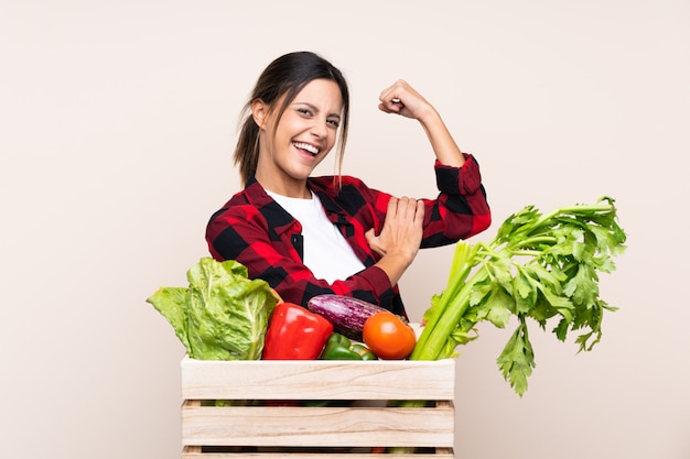 Agriculteur femme tenant des légumes frais dans un panier en bois faisant un geste fort