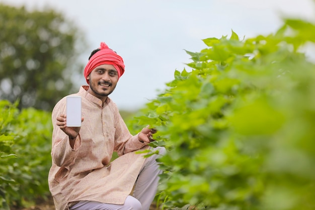 Agriculteur indien montrant l'écran du smartphone au domaine de l'agriculture