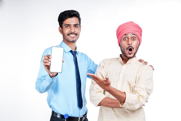 Agriculteur indien montrant smartphone avec agent sur fond blanc.