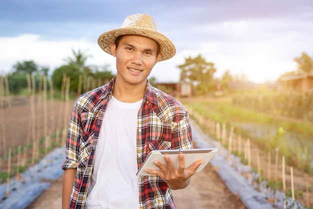 Agriculteur intelligent asiatique tenant la tablette dans sa ferme biologique.