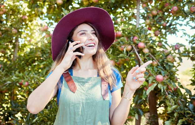 Agriculteur joyeux parlant au téléphone tout en planifiant des tâches pour la saison de récolte de fruits biologiques frais