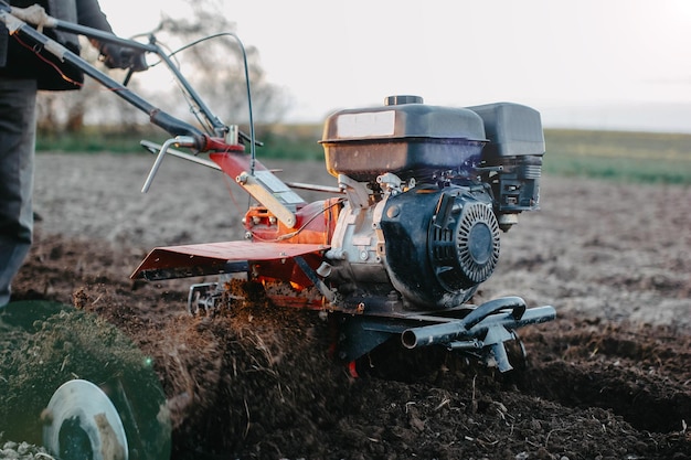 un agriculteur laboure la terre avec un tracteur à conducteur marchant dans l'agriculture domestique du village