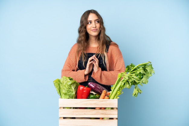 Agriculteur avec des légumes fraîchement cueillis dans une boîte complotant quelque chose