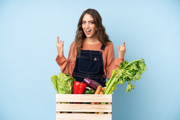 Agriculteur avec des légumes fraîchement cueillis dans une boîte faisant un geste rock