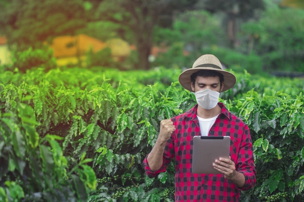 Agriculteur avec masque et tablette pandémique covid sur la ferme de plantation