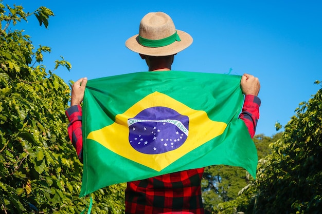 Photo agriculteur à la plantation de café tenant le drapeau brésilien