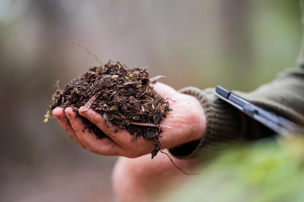 agriculteur portant un chapeau étant intelligent au soleil en utilisant la technologie et une tablette et un téléphone dans un champ étudiant un échantillon de sol et de plante dans le champ