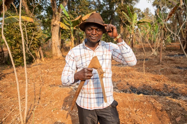 Un agriculteur prospère dans son champ tient la houe dans sa main