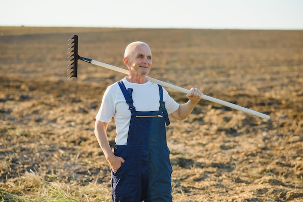 Un agriculteur senior travaille dans un champ avec de la terre