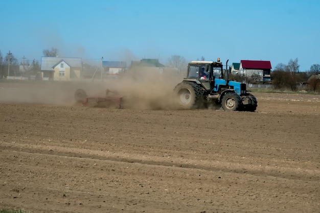Agriculteur en tracteur préparant la terre avec un semoir dans le cadre des activités de pré-ensemencement au début de la saison des travaux agricoles sur les terres agricoles