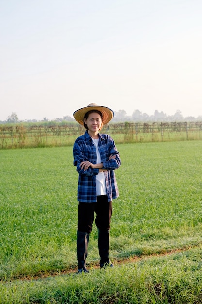 Une agricultrice asiatique se tient au milieu d'un champ le matin