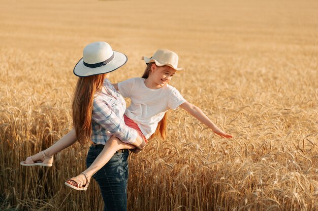 Une agricultrice avec un chapeau tient son enfant dans ses bras femme et enfant dans la famille du champ de blé doré o...