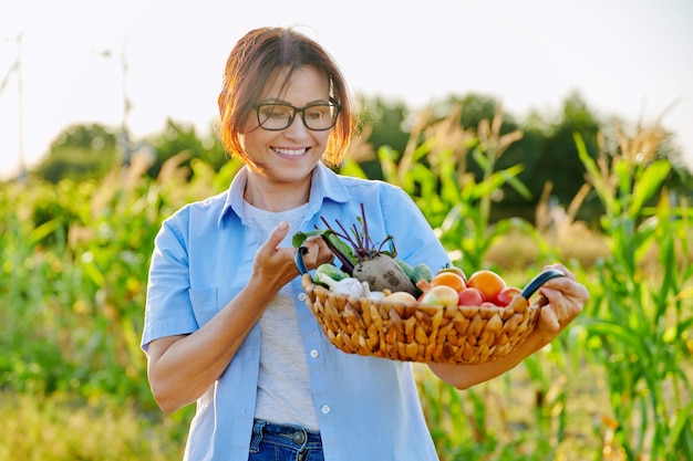 Agricultrice jardinière d'âge moyen avec panier de légumes mûrs