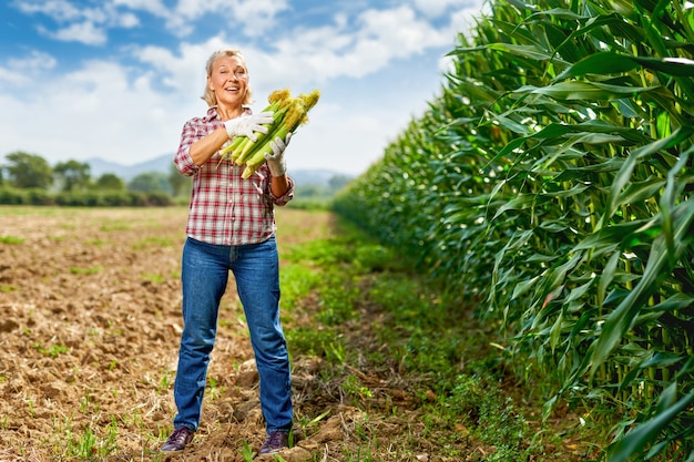 Agricultrice tenant une récolte de maïs dans ses mains.