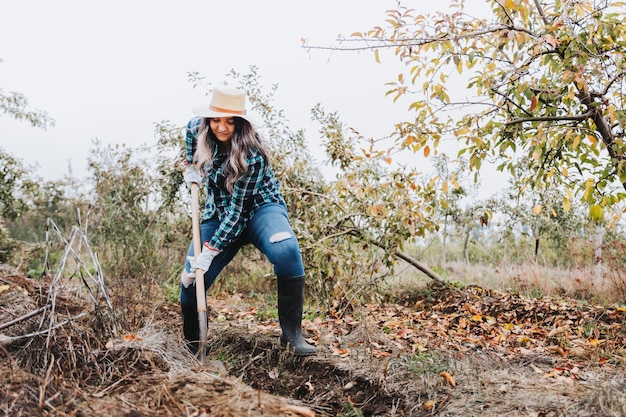 agricultrice utilisant la pelle pour creuser un sillon dans le sol