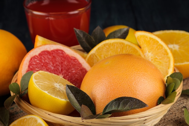 Agrumes. Différents agrumes avec des feuilles de citron, d'orange, de pamplemousse dans un panier et de jus sur une table en bois bleue.