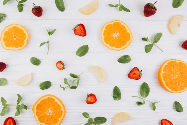 agrumes, feuilles et fraises sur la table en bois bleue.