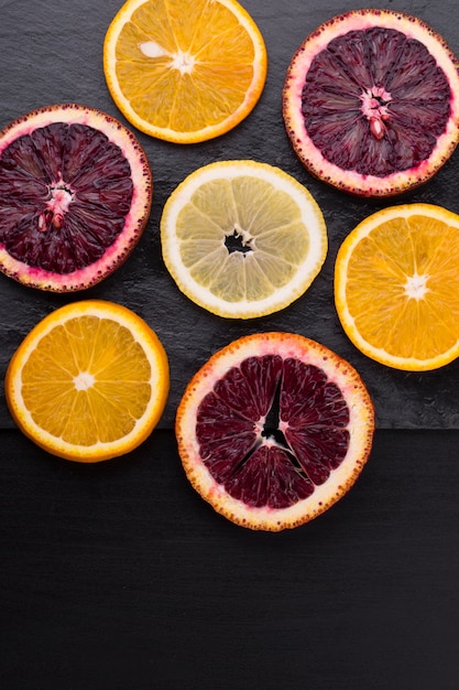 Agrumes frais et mûrs. Citrons, oranges rouges et oranges sur table en pierre sombre. Espace copie