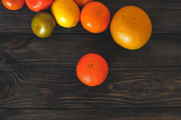 Agrumes pamplemousse, orange, mandarine sur fond de planches de bois.