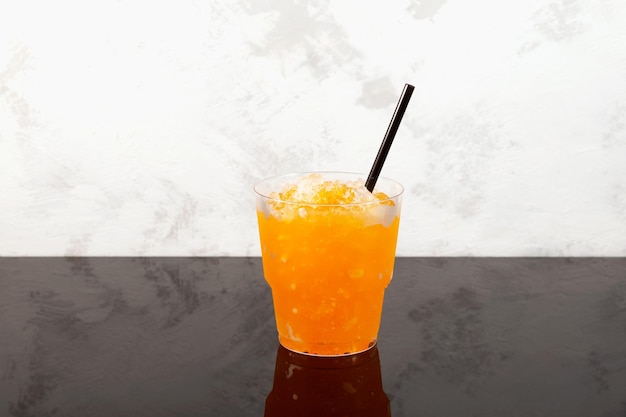 Agrumes sucrés Glace rasée Orange Granizado dans une tasse à emporter en plastique Boisson rafraîchissante Slushie