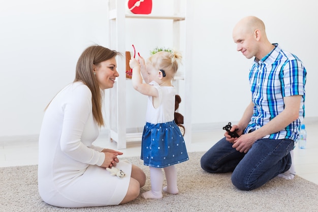 Aide auditive dans l'oreille d'une petite fille. Enfant en bas âge portant une prothèse auditive à la maison.