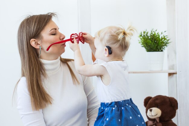 Aide auditive dans l'oreille d'une petite fille. Enfant en bas âge portant une prothèse auditive à la maison.