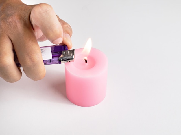 À l'aide d'un briquet une mèche de bougie rose utilisée dans certains festivals Le feu donne de la chaleur lumière espoir