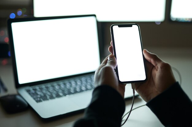 À L'aide De Gadgets Gros Plan Sur Un écran Blanc Vierge D'un Homme Intelligent Assis Dans Une Pièce Sombre Devant