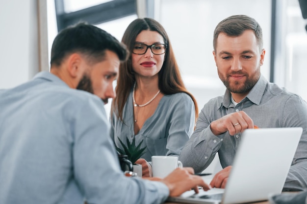 À l'aide d'un ordinateur portable Groupe de gens d'affaires qui travaillent sur le projet au bureau