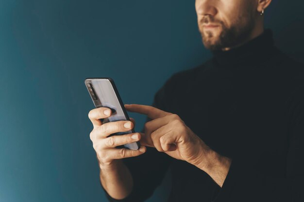 À l'aide d'un smartphone par un jeune homme sur un fond blanc Téléphone à la main lors de l'utilisation d'Internet