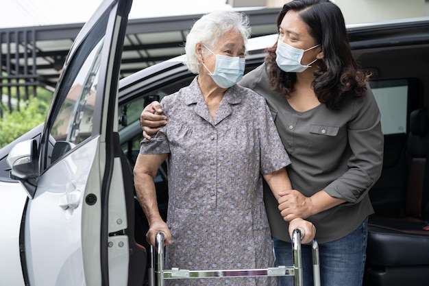 L'aide soignante et le soutien d'une vieille dame asiatique ou d'une vieille dame patiente marchant avec une marchette se préparent à se rendre à sa voiture concept médical fort et sain