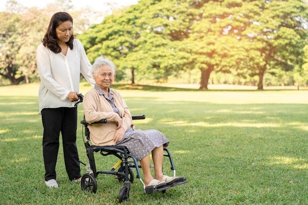 Aide et soins aux soignants Asiatiques seniors ou personnes âgées vieille dame patiente assise sur un fauteuil roulant dans le parc sain concept médical fort