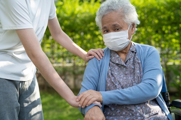 Aide et soins aux soignants Asiatiques seniors ou personnes âgées vieille dame patiente assise sur un fauteuil roulant dans le parc sain concept médical fort