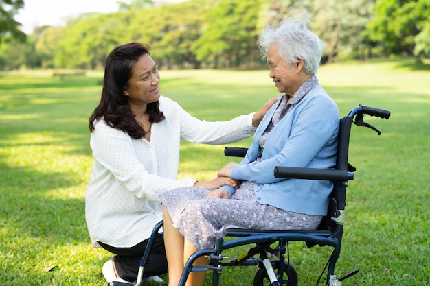 Aide et soins d'un soignant Une femme âgée asiatique utilise un déambulateur en bonne santé tout en marchant au parc pendant de joyeuses vacances fraîches