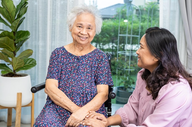 Aide et soins des soignants Asiatiques seniors ou personnes âgées vieille dame patiente assise sur un fauteuil roulant à la maison