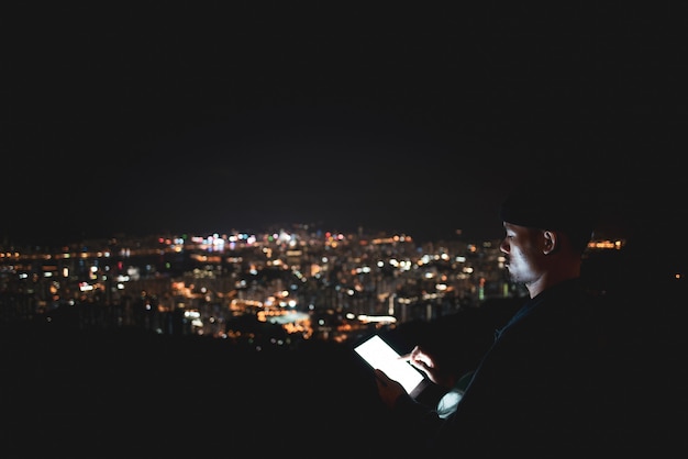 À l&#39;aide d&#39;une tablette sur la vue sur la ville de montagne la nuit