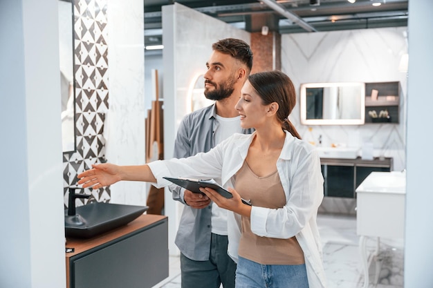 Aider à choisir le bon produit La femme et l'homme sont dans le magasin de produits pour la maison