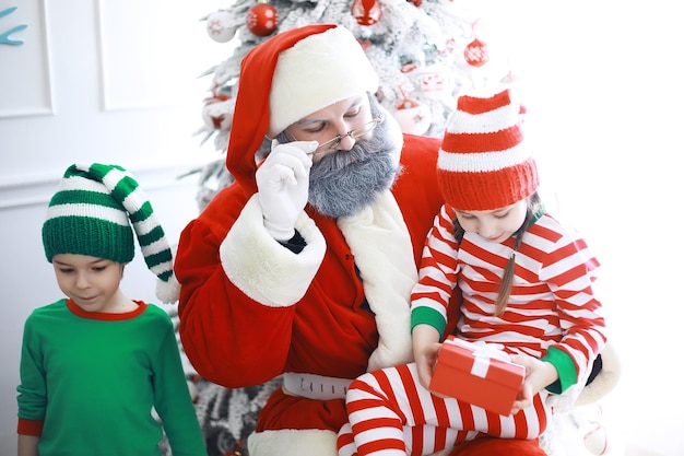 Aides du Père Noël. Enfants mignons en costumes de lutin de Noël dans une pièce joliment décorée pour Noël. Le temps des miracles. Cadeaux du Père Noël.