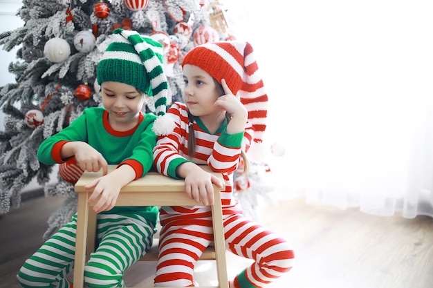 Aides du Père Noël. Enfants mignons en costumes de lutin de Noël dans une pièce joliment décorée pour Noël. Le temps des miracles. Cadeaux du Père Noël.