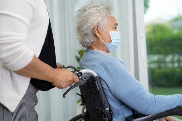 Aidez une femme âgée asiatique assise sur un fauteuil roulant et portant un masque facial pour protéger le coronavirus