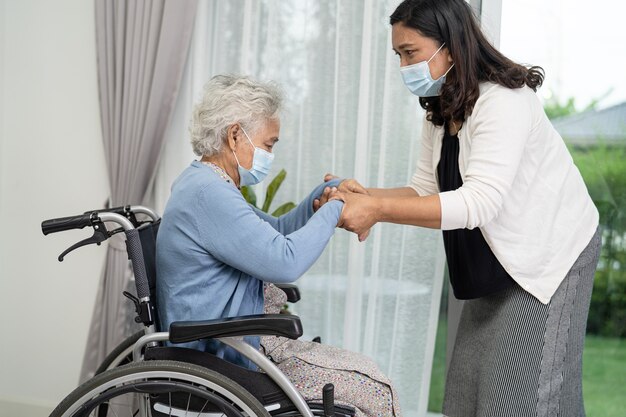 Aidez une femme âgée asiatique assise sur un fauteuil roulant et portant un masque pour protéger le coronavirus