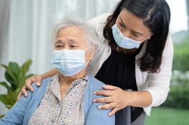 Aidez une vieille dame asiatique âgée ou âgée assise sur un fauteuil roulant et portant un masque facial pour protéger la sécurité de l'infection Covid19 Coronavirus