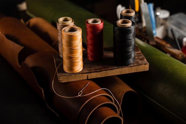 Aiguille avec bobines de fil sur rouleau de cuir véritable marron dans l'atelier de l'artisan Production de cuir véritable fait main dans l'usine