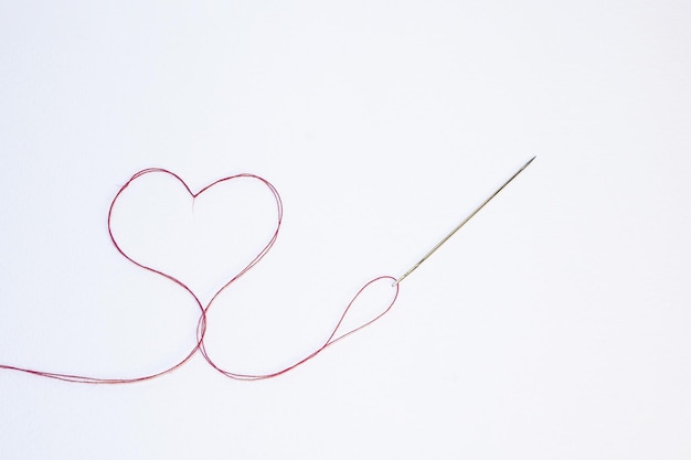 Photo une aiguille formant un cœur avec un fil rouge