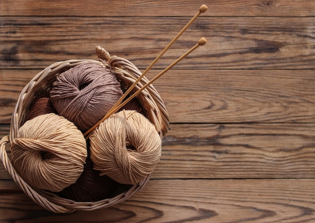 Aiguilles à tricoter et fil dans un panier en osier sur fond de bois Journée de l'artisanat