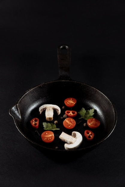 Ail ail sur fond noir avec tomates et champignons